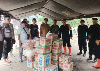 BERI BANTUAN: Brimob Polda Sumut memberikan bantuan sembako kepada warga terdampak banjir akibat tanggul sungai jebol. (Foto Dok/ Polda Sumut)