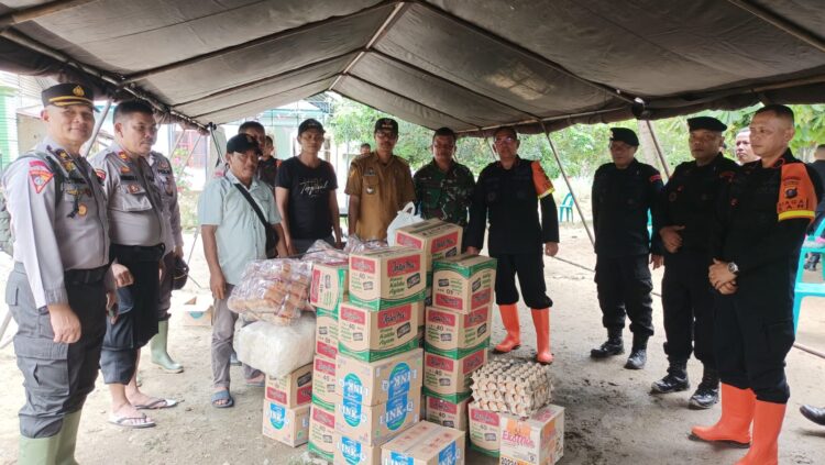 BERI BANTUAN: Brimob Polda Sumut memberikan bantuan sembako kepada warga terdampak banjir akibat tanggul sungai jebol. (Foto Dok/ Polda Sumut)